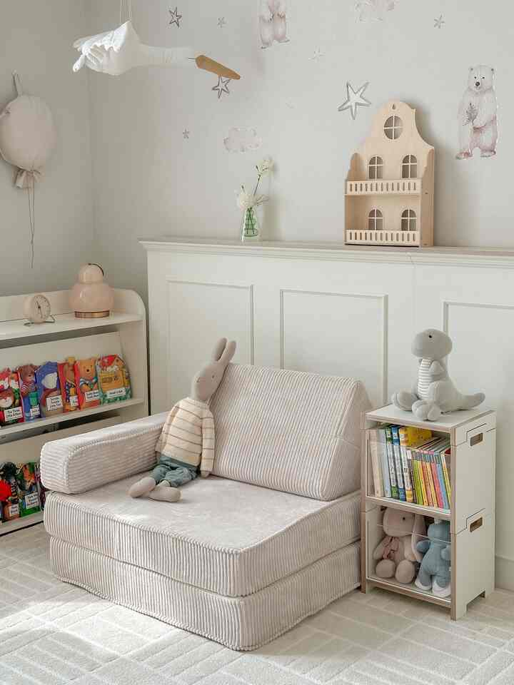 柔らかなホワイトとナチュラルカラーの子供部屋、赤ちゃんのぬいぐるみと本棚が整った印象的な空間