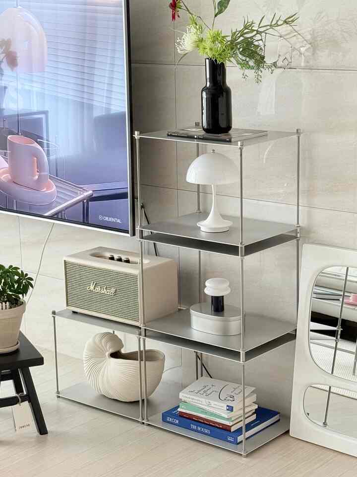 白とシルバーの色調のリビング、モジュールシェルフとテレビ、さまざまな装飾品が配置された印象的なモダンインテリア