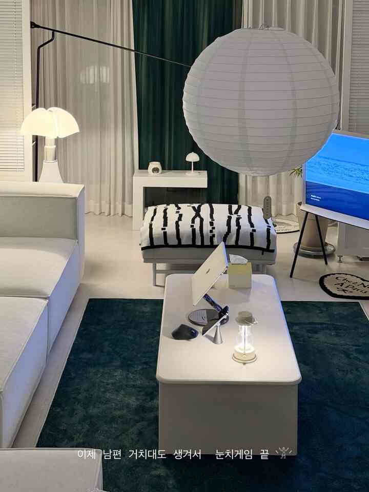 白とネイビーのトーンのモダンで落ち着いたリビング、ソファとテーブルランプ、ラグが配置された空間