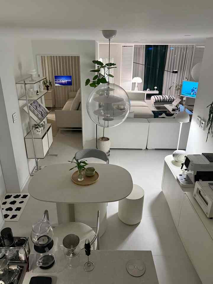 白とグレーを基調としたリビングとダイニング、コーナーソファとセラミックテーブル、コーヒーマシンが配置されたモダンで清潔感のあるインテリア