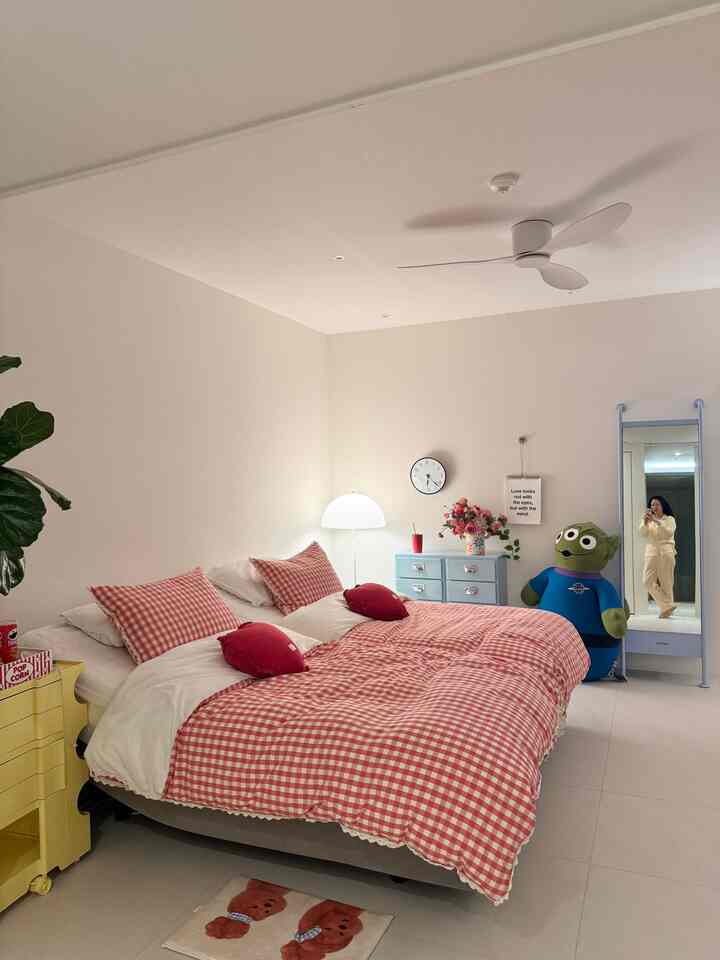 白い壁と赤のチェック柄寝具が配置された北欧風の寝室、全身鏡とライトブルーのチェストが印象的な空間