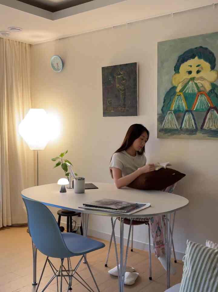 暖かいベージュとホワイトの色調のリビング兼ダイニングスペース、ブルーチェアとフロアランプが調和した落ち着いた読書空間