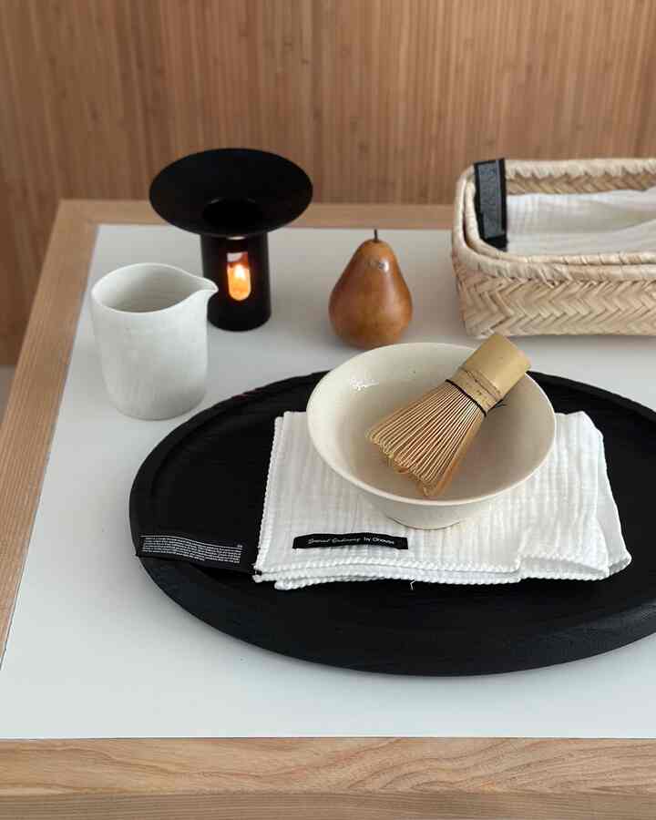 ウッドトーンの背景に黒い木製トレイと白い器、キッチン小物が整然と配置されたモダンなインテリア写真