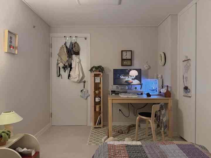 アイボリーと木目調が調和した一人暮らしのホームオフィス兼寝室、シンプルモダンな雰囲気のある空間