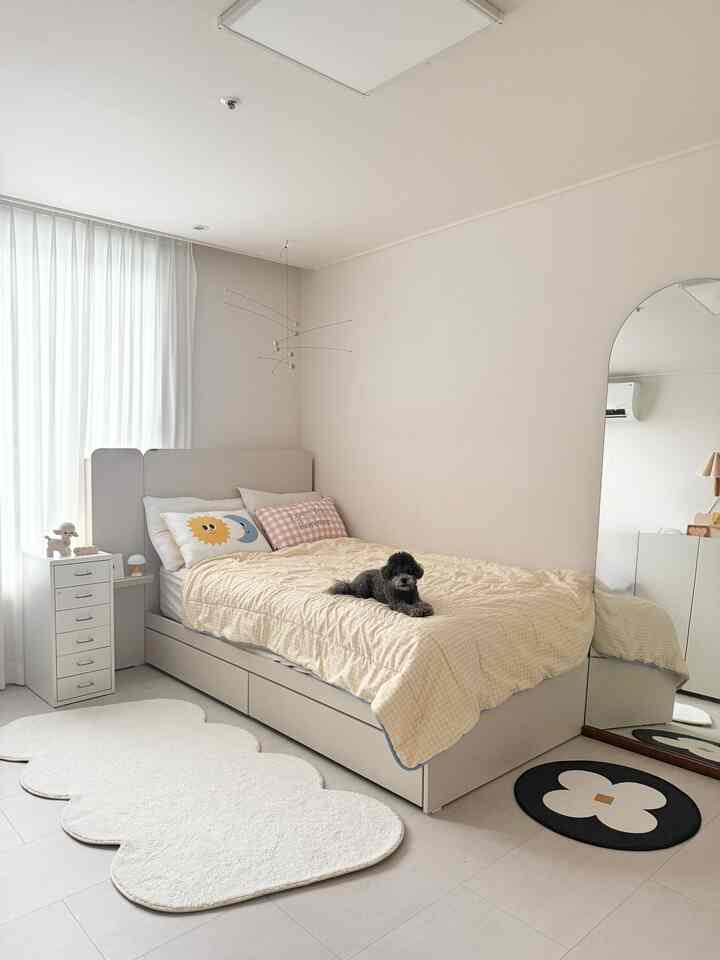 ベージュ調の寝室、大きなアーチ型の鏡やベッド、チェストが配置されたシンプルで自然な雰囲気のインテリア