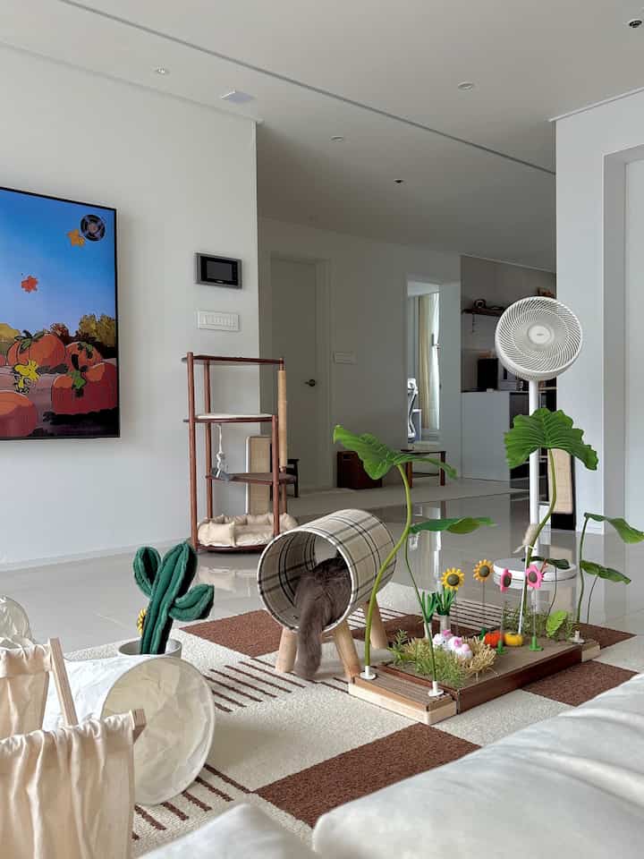 白と茶色のトーンのリビング、猫用トンネルや爪とぎなどペット家具が配置された自然で雰囲気のあるインテリア