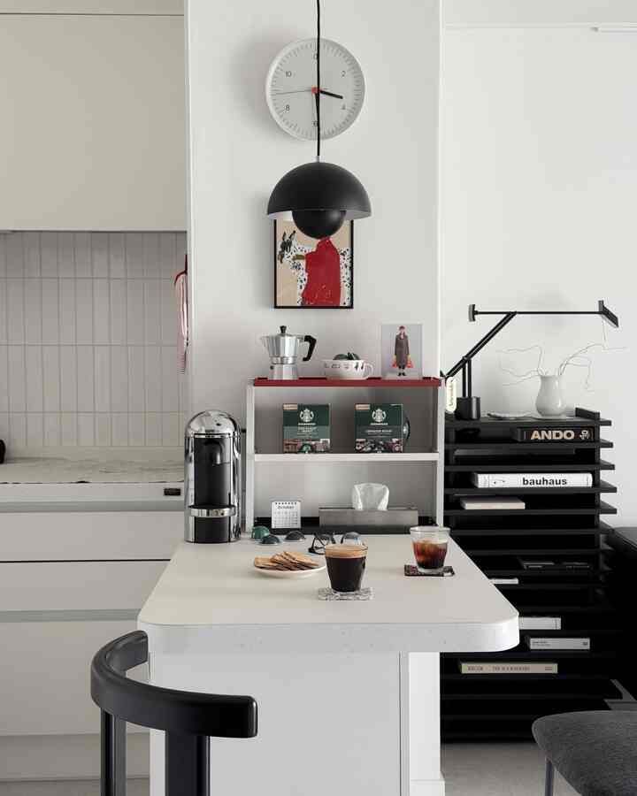 白と黒のトーンのキッチンとおうちカフェ空間、コーヒーマシンとダイニングテーブルが配置されたモダンなインテリア