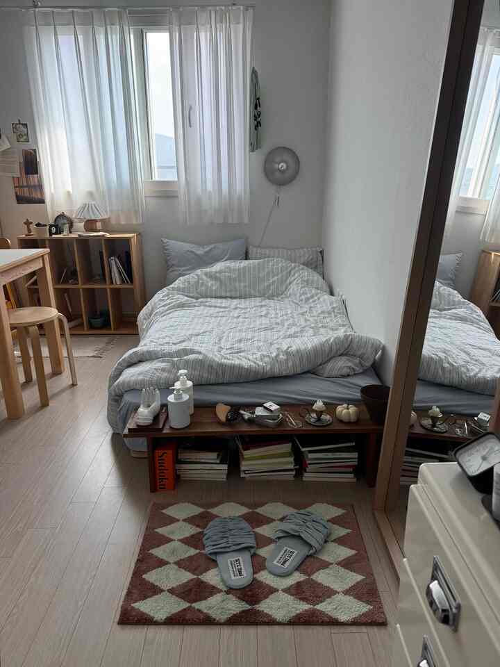 明るいベージュと木目調の寝室、窓際に白いシフォンカーテンと木製家具が配置されたナチュラルモダンなインテリア