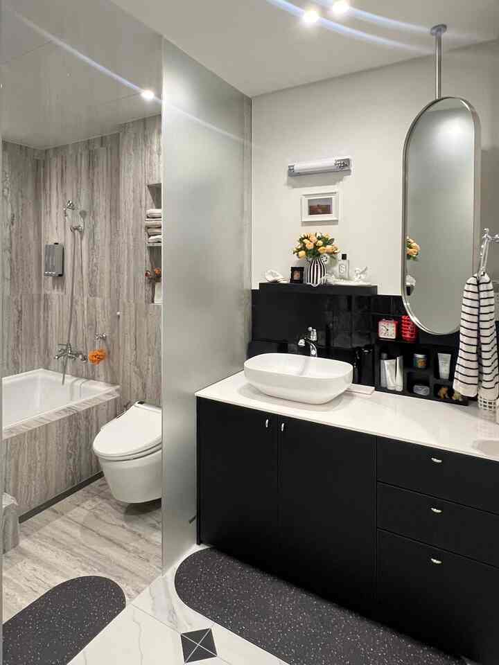 A modern bathroom and powder room in white and black tones featuring a sink with mirror, bathtub, and toilet