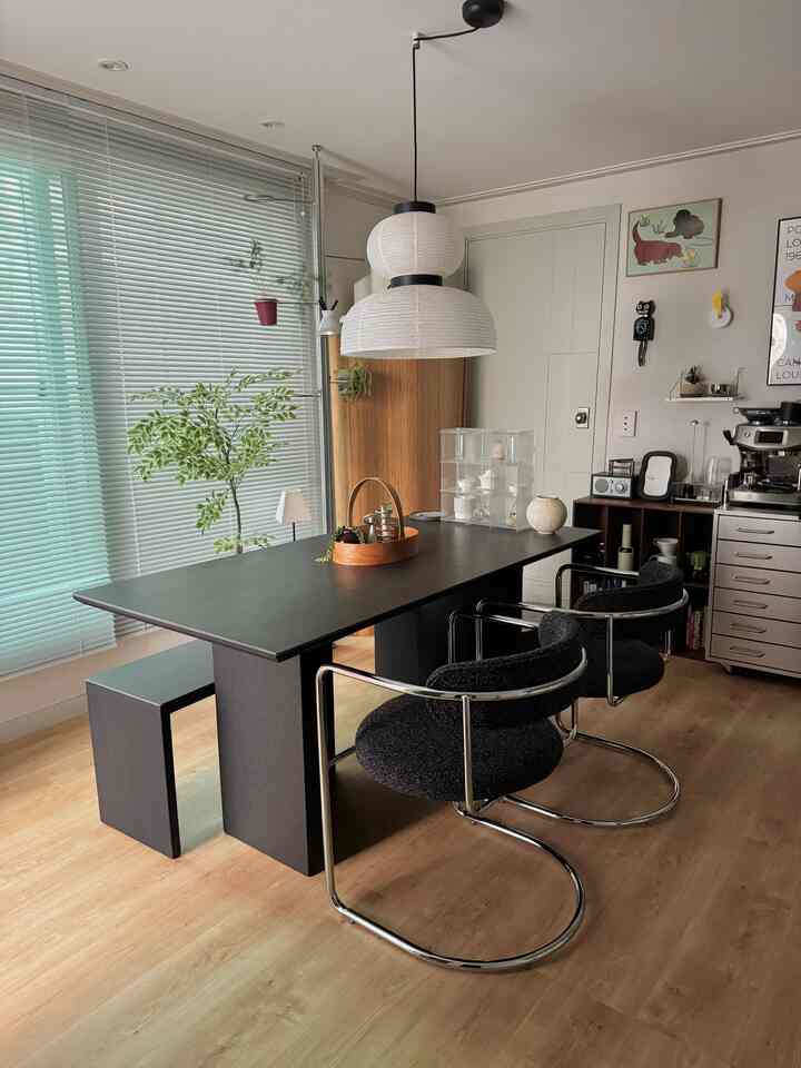 木目調の床と黒い長方形のダイニングテーブル、ペンダントライトが配置されたモダンなダイニングルームのインテリア