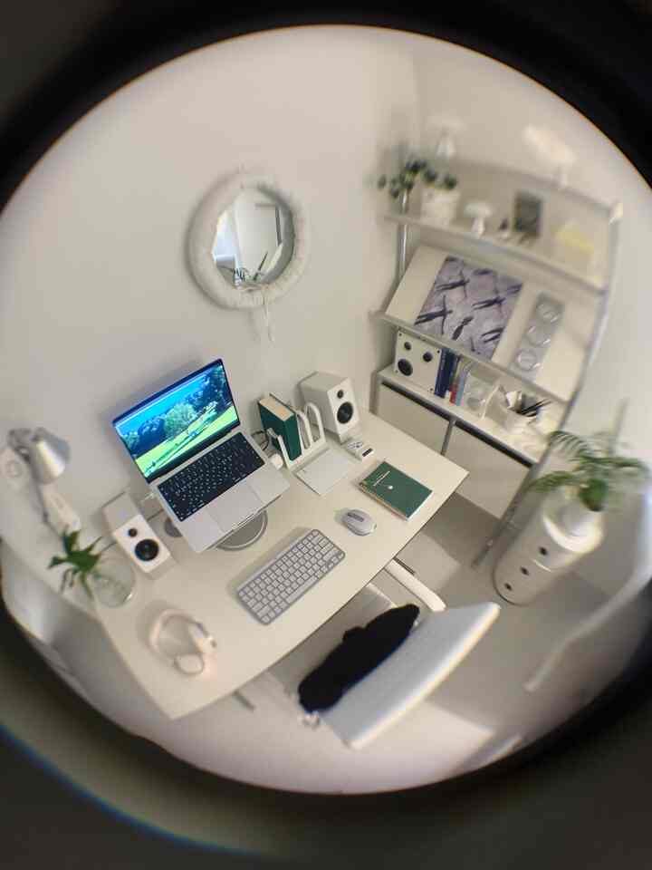 白を基調としたコンパクトなホームオフィス、シンプルなデスクとチェア、ノートパソコンやスピーカーが配置されたミニマルな雰囲気のインテリア