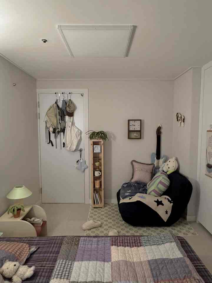 Ivory-toned studio small room featuring a black single sofa and a patchwork bedspread, cozy atmosphere