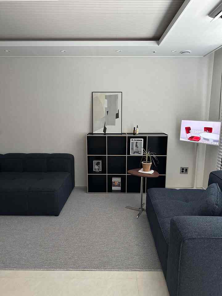 チャコールとグレーの色調のモダンなリビング、2つの黒いソファと黒の収納が調和した印象的な空間