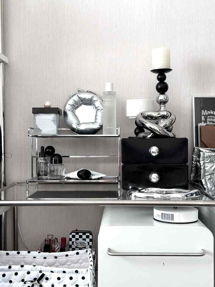 ホワイトとシルバーのトーンが特徴的なモダンな化粧台スペース、クロム製の棚と黒い収納箱が整然とした印象のインテリア