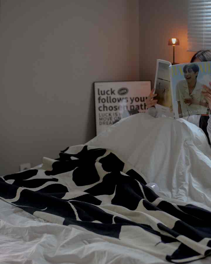 黒と白のトーンの寝室、パターンのブランケットと温かみのある照明が配置された雰囲気のあるインテリア