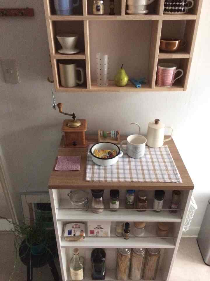 ナチュラルな色調のキッチン、壁棚と木製テーブルにコーヒーミルやマグカップが配置された雰囲気のあるおうちカフェ
