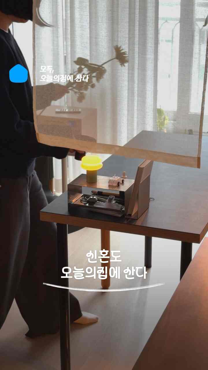 ナチュラルカラーとチャコール色調の一人暮らしダイニングスペース、カーテンとテーブル、ホームカフェ風の照明が配置された雰囲気のあるインテリア