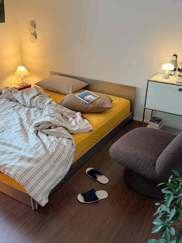 黄色いマットレスと木目調の床が調和したモダンな寝室、温かみのある落ち着いた空間