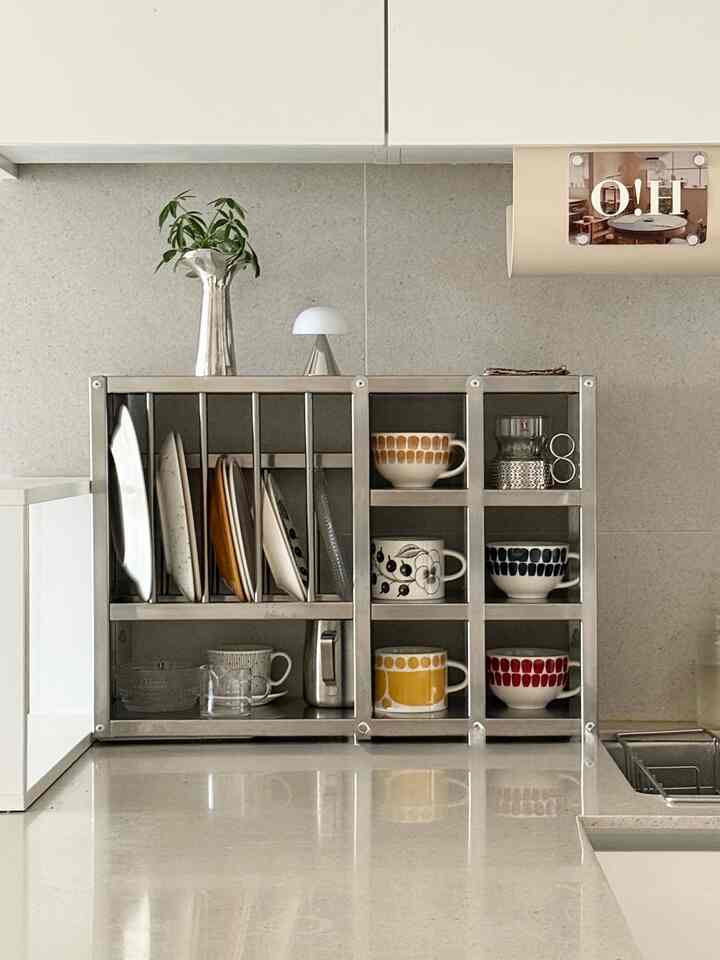 ベージュ色調のキッチン、整理された収納キャビネットに皿とマグカップが置かれた雰囲気のあるナチュラルモダンなインテリア