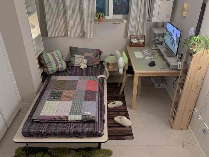 ナチュラルな色調のワンルーム寝室、ベッドとデスク、照明が調和した居心地の良い空間