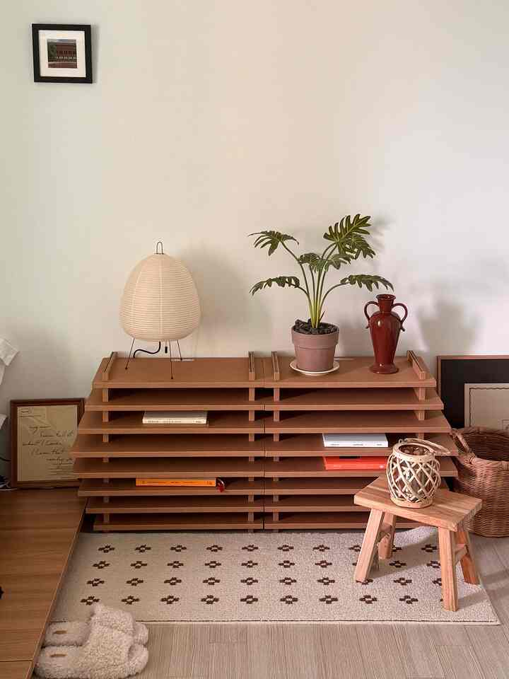 ナチュラルな色調の寝室コーナー、木目調の小物と植物、スツールが配置された雰囲気のあるインテリア