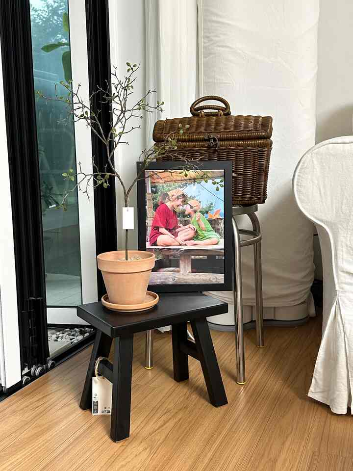 ブラウンの木目調の床と黒いスツールに置かれた植物があるダイニングルームの温かみのあるコーナー