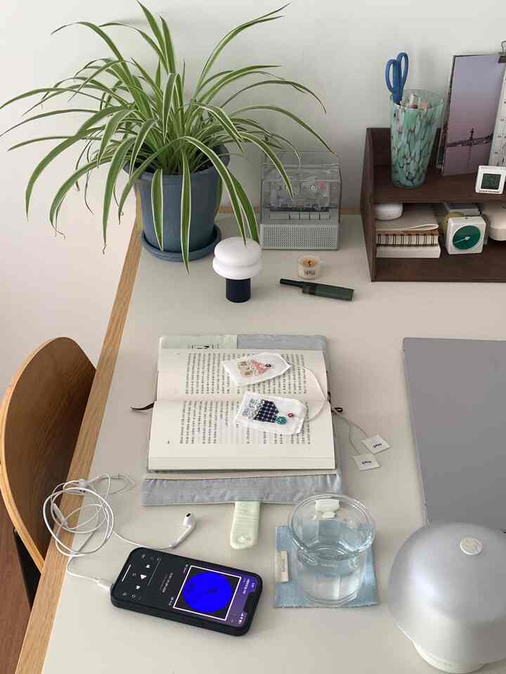 白を基調とし、木目調の家具が配されたホームオフィスのデスクスペース。観葉植物と本が温かみのある雰囲気を演出