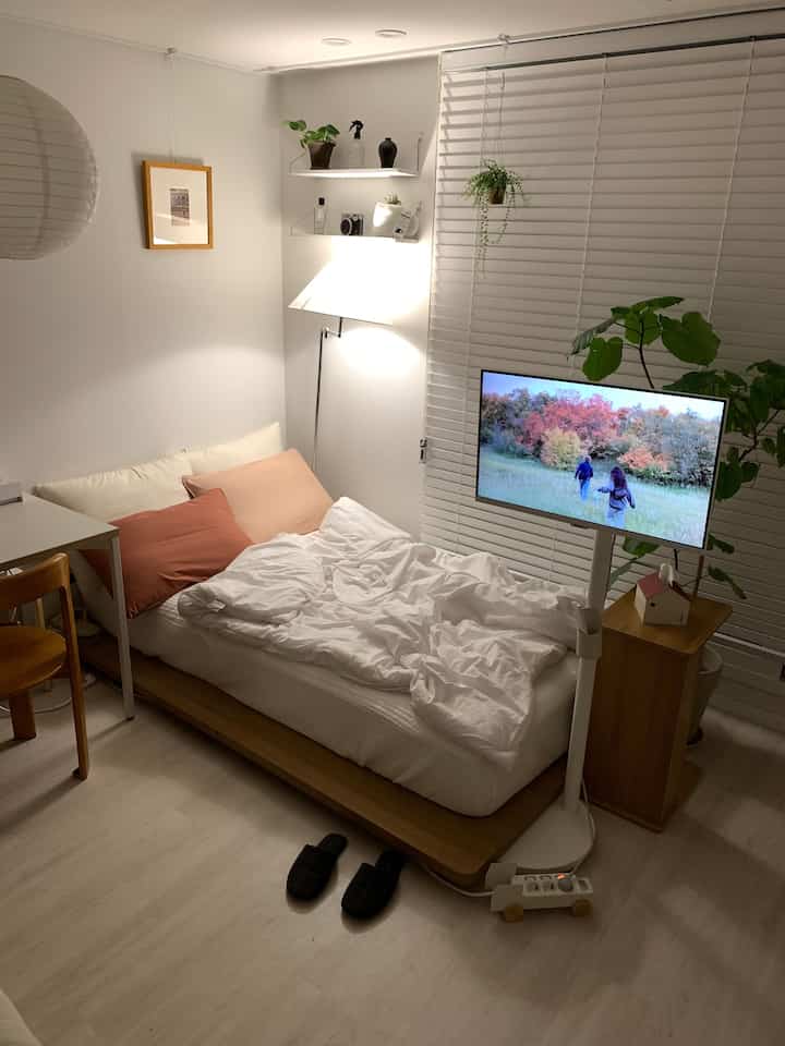 白と木目調の色調が調和した一人暮らしの寝室、ミニマルな家具と落ち着いた雰囲気のインテリア