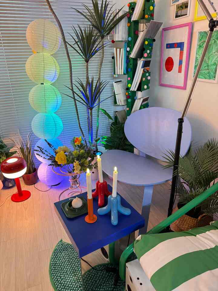 パステルブルーのアームチェアと多様な植物が配置された居心地の良いカラフルなリビングスペース