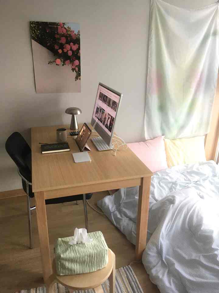 木目調と白を基調とした寝室兼ホームオフィス、コンピュータデスクとベッドが配置された落ち着いた空間