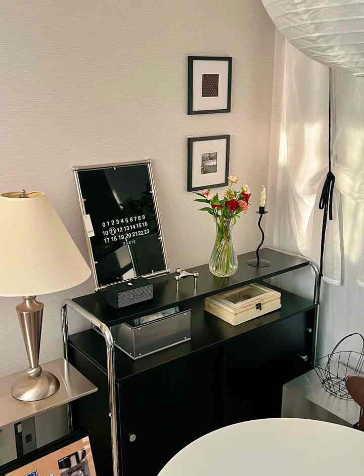 黒とシルバーのトーンが特徴的なリビング、サイドボードに花瓶とキャンドルが置かれたモダンなインテリア