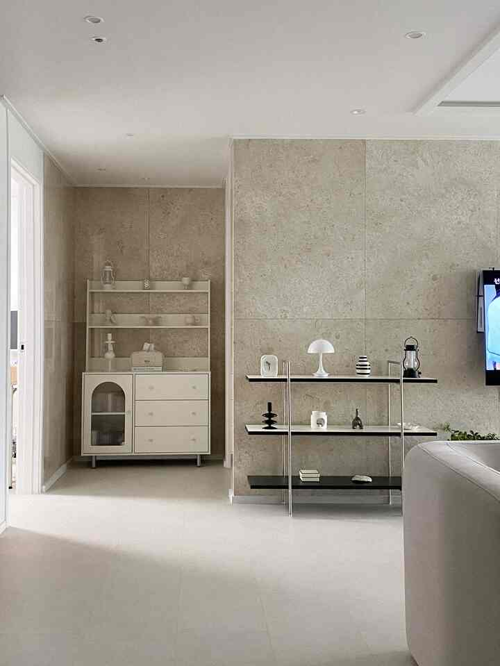 ベージュ色の壁と床、白いキャビネットと棚が配置されたナチュラルでモダンなリビング