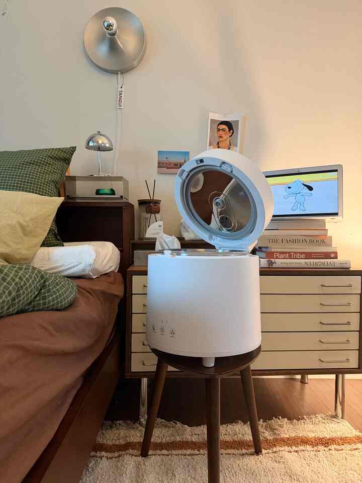 ナチュラルなブラウンとホワイトの寝室、ベッドとナイトテーブルに加湿器や照明が配置された暖かみのあるインテリア