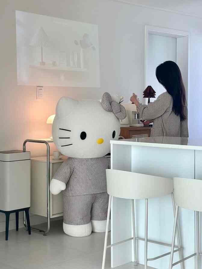 ホワイトとブラウンのトーンでまとめられたキッチンとホームバーの空間、大きなハローキティの人形とバースツールが配置された印象的なインテリア