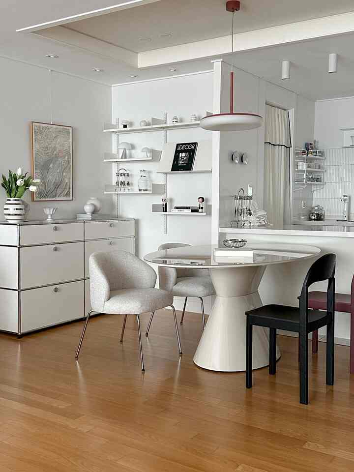 明るい木目調の床と白い壁のモダンなキッチン・ダイニング、中央に円形のダイニングテーブルと複数の椅子が配置された清潔感のある空間