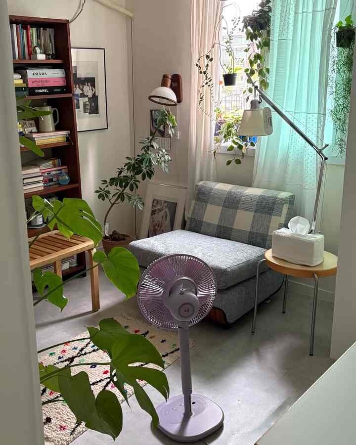 グリーンの植物とブルートーンのカーテンがあるコンパクトでヴィンテージ風の一人暮らしリビング