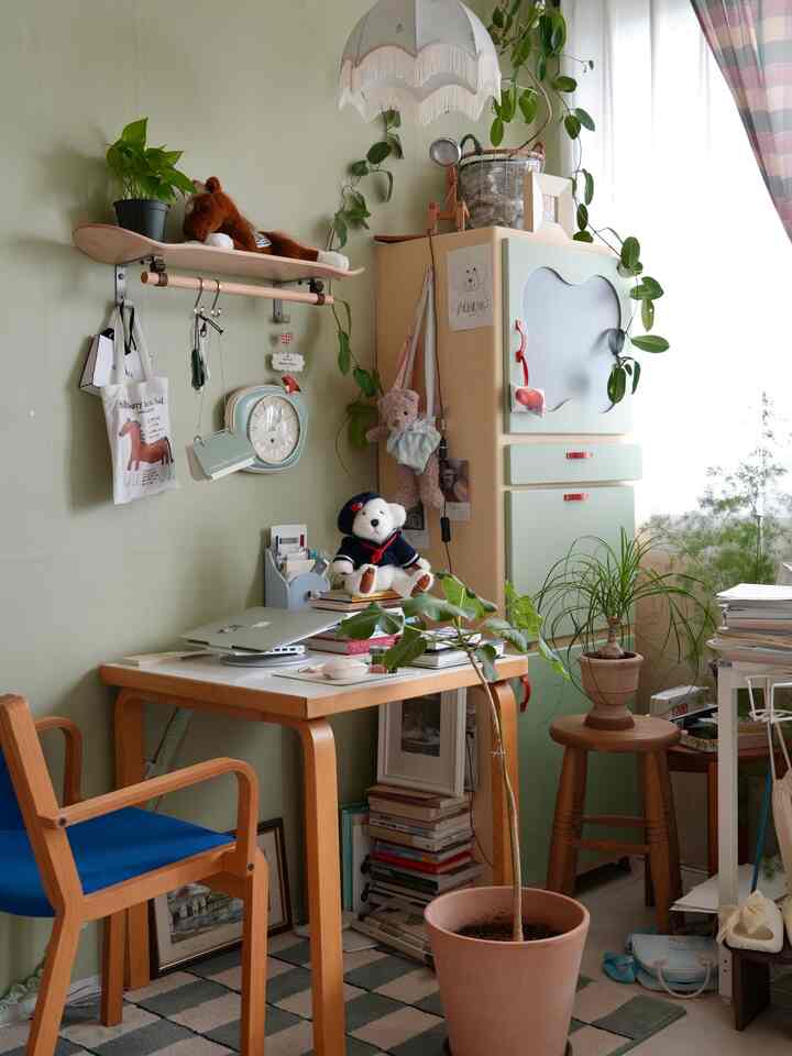 柔らかなグリーンの壁とナチュラルウッドの家具、植物が配置された居心地の良いホームオフィス