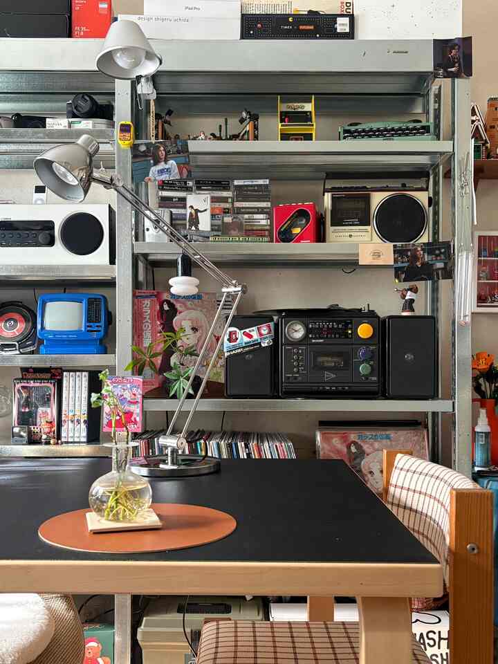 黒いテーブルと木目調の椅子が配置された空間、メタルシェルフとビンテージレトロ小物が雰囲気あるリビングを演出