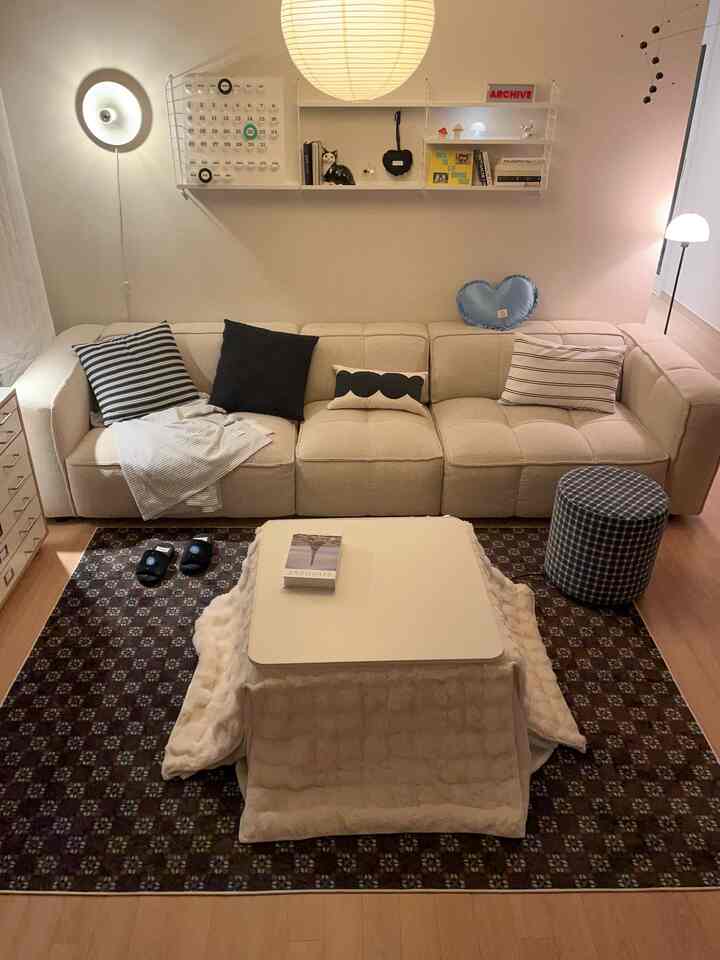 ベージュとホワイトの色調のリビング、ベージュのソファと中央にこたつテーブルが配置された雰囲気のあるインテリア