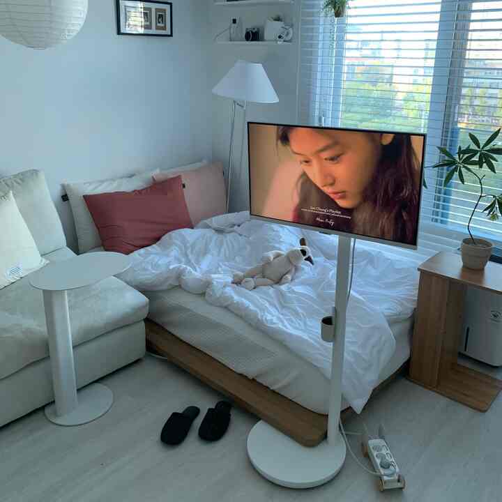 白とベージュのトーンで統一された6坪のワンルーム寝室、低床ベッドとクリーム色のソファ、移動式テレビスタンドが配置された落ち着いた雰囲気のあるインテリア