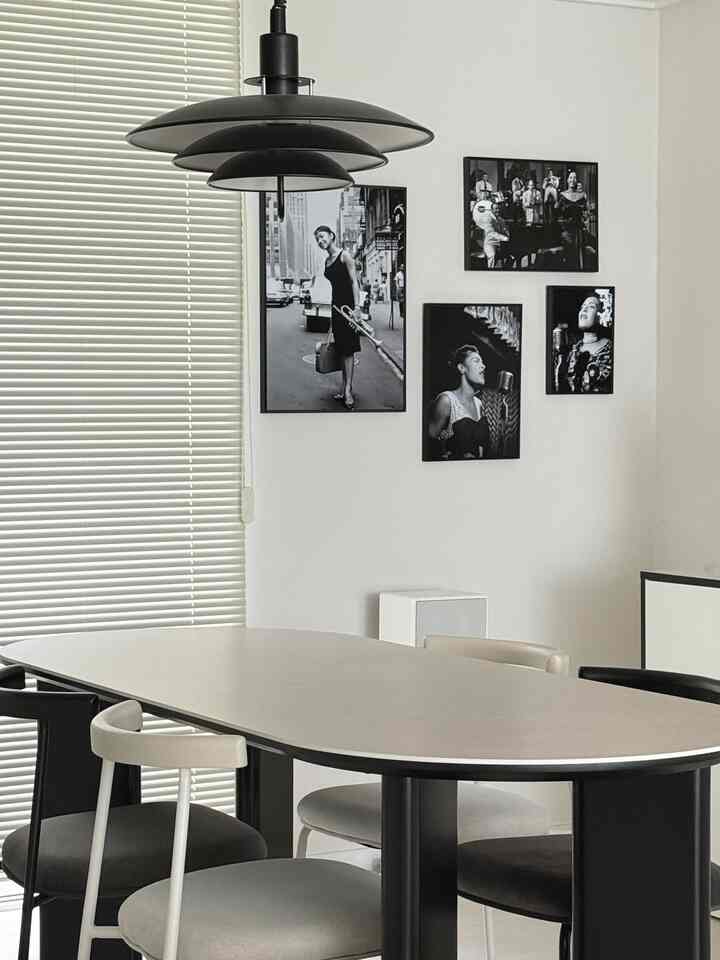 クリームベージュの楕円形ポーセリンダイニングテーブルとモダンな黒とクリーム色のエルシーチェアが配置された白いキッチン空間