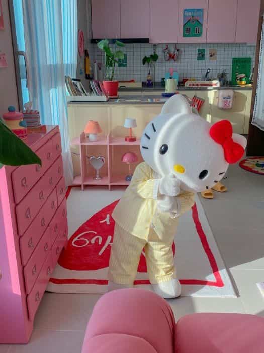 ピンクと白の色調のリビング兼子供部屋、キャラクターラグと赤ちゃんの人形が配置された温かみのある空間