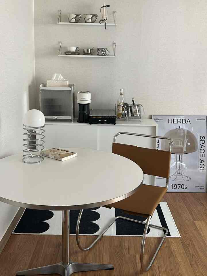 白と茶色の色調のダイニングスペース、ミッドセンチュリーモダンな小物とミニマルな雰囲気のインテリア