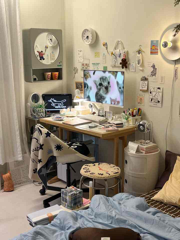 ホワイトとウッドトーンのホームオフィス、デスクとスツール、猫モチーフのアクセントがある雰囲気のある一人暮らしの部屋