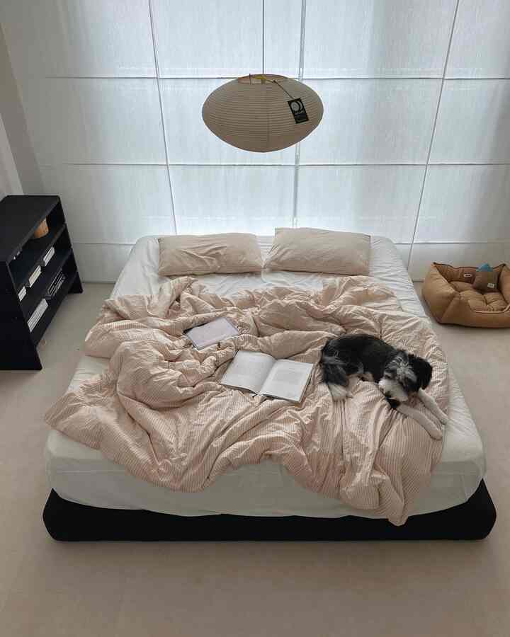 ベージュと白のトーンの寝室、大きなベッドとカーテン、ペンダントライトが配置された自然なモダンなインテリア