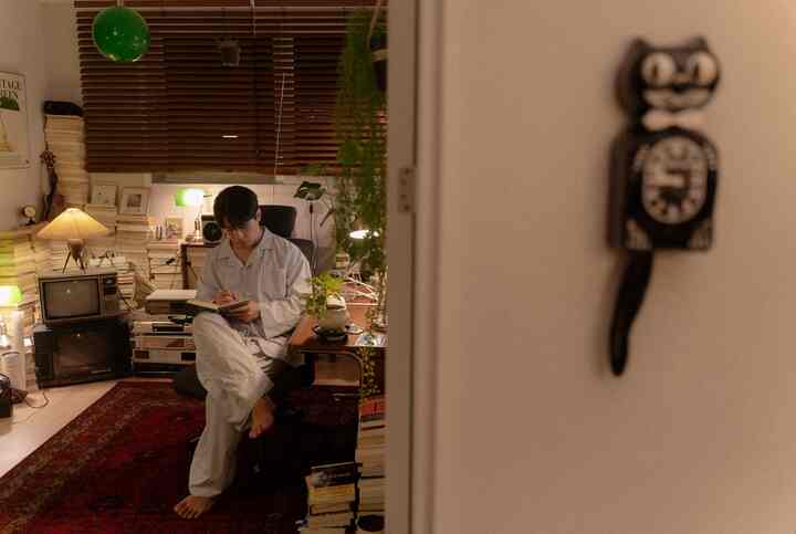 暖かいブラウンとレッドの色調のリビング書斎、机とオフィスチェアに座り読書している居心地の良い空間
