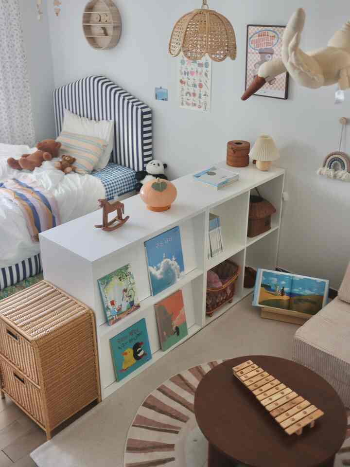 ナチュラルな木の色調と白を基調とした子供部屋、本棚やベッド、玩具が配置された温かみのあるインテリア