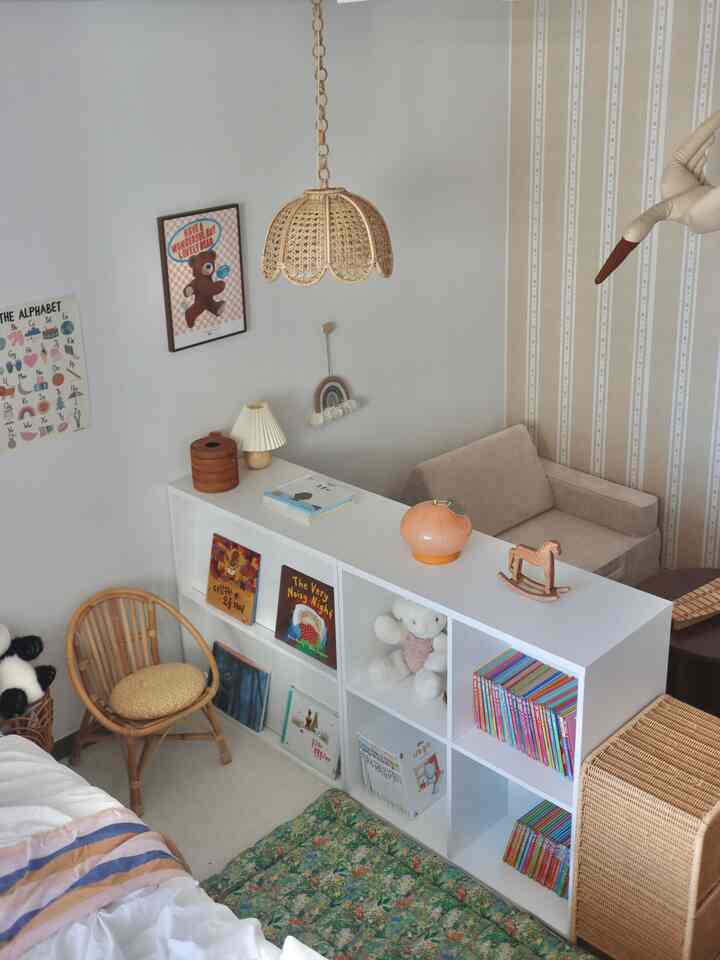 白とラタンの色調の子供部屋、両面本棚が空間を分け、居心地の良い読書と睡眠スペースが配置された雰囲気のあるインテリア