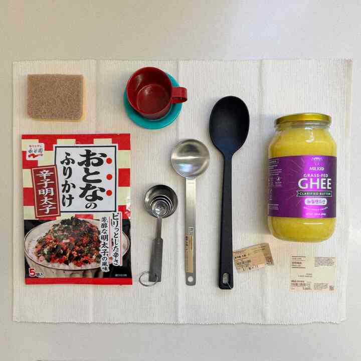 ナチュラルな色調のキッチン、白い木綿のキッチンタオルの上にシリコン調理スプーンとステンレス計量スプーンが整然と配置された雰囲気のあるインテリア