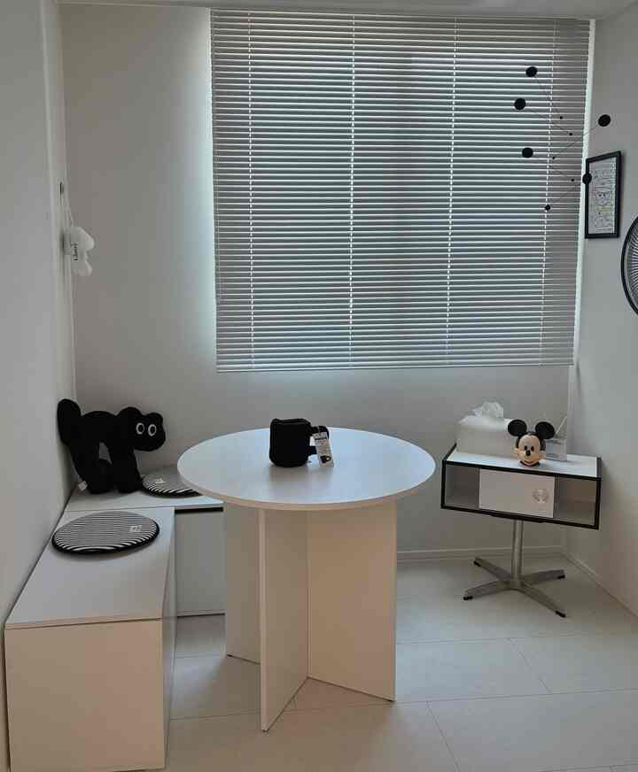 白のモノトーンが基調の子供部屋、丸いダイニングテーブルとサイドテーブルが配置された清潔感のあるモダンなインテリア